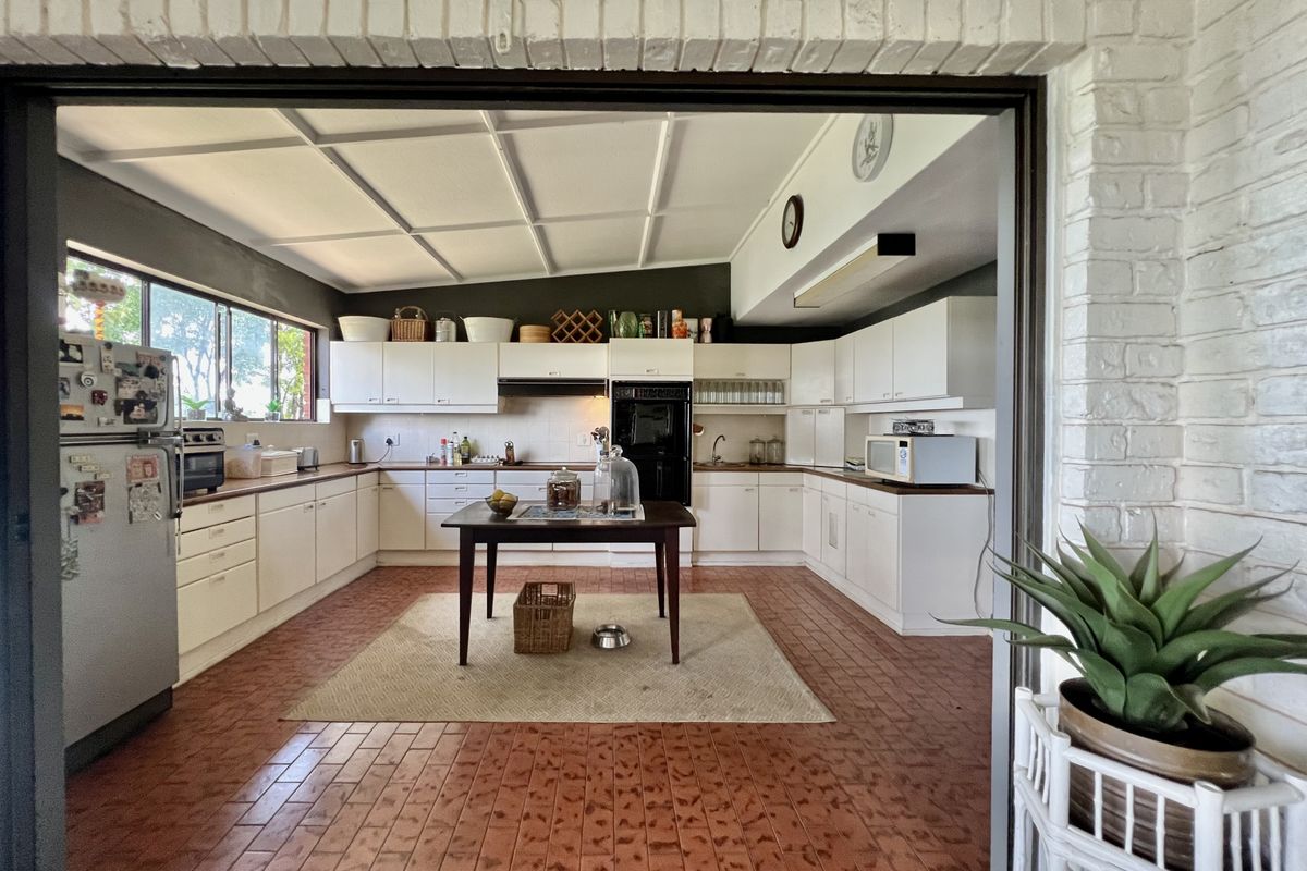 Spacious kitchen featuring white built-in cabinetry, integrated oven, extractor fan, and tiled flooring, offering a functional layout with ample counter space.