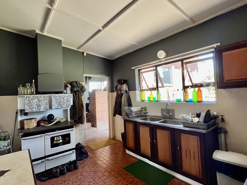 A rustic kitchen featuring a built-in stove, extractor fan, double basin sink, and traditional cabinetry, offering a functional space with potential for modern updates.