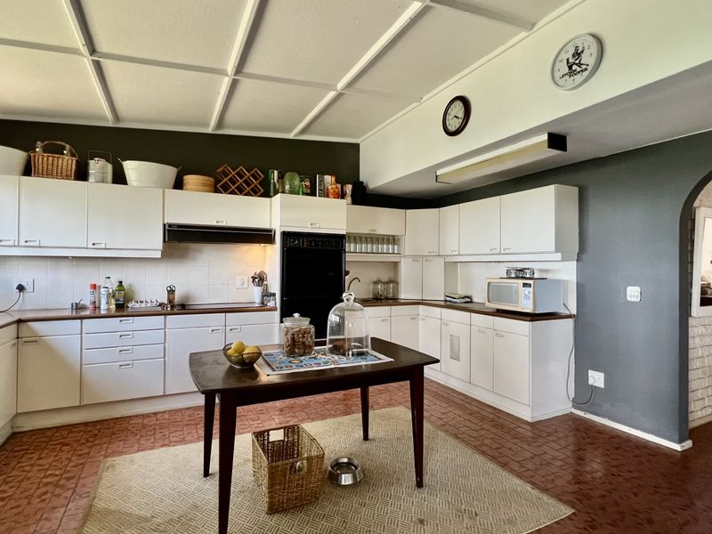 Spacious kitchen featuring white built-in cabinetry, laminate countertops, integrated oven, and tiled flooring, offering a functional layout with an adjacent arched entryway.