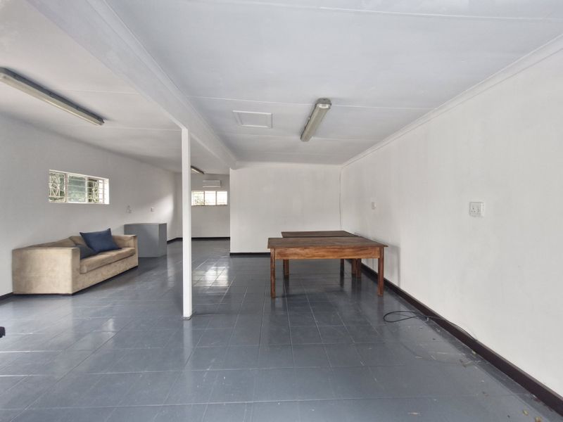 Spacious open-plan commercial area featuring tiled flooring, fluorescent lighting, and an air conditioning unit, suitable for various office or retail configurations.