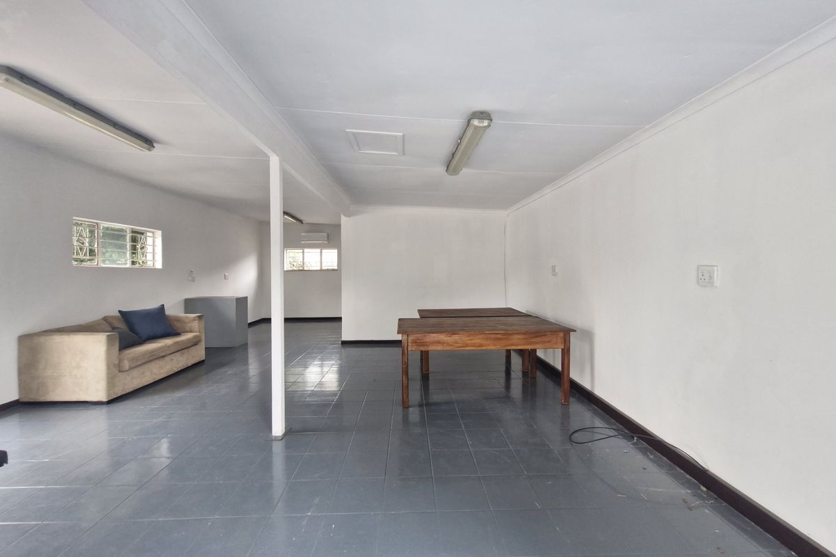 Spacious open-plan commercial area featuring tiled flooring, fluorescent lighting, and an air conditioning unit, suitable for various office or retail configurations.