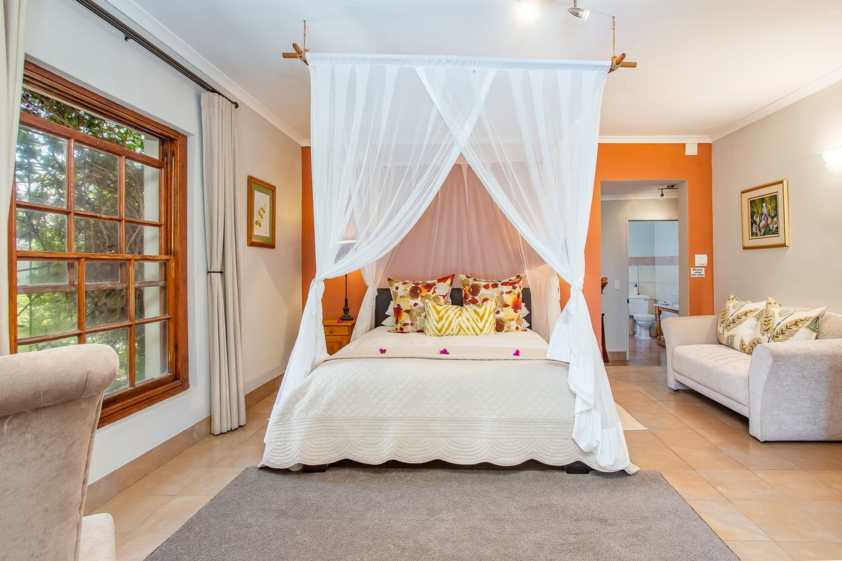 Spacious bedroom featuring tiled flooring, timber-framed windows, and direct access to an en-suite bathroom.