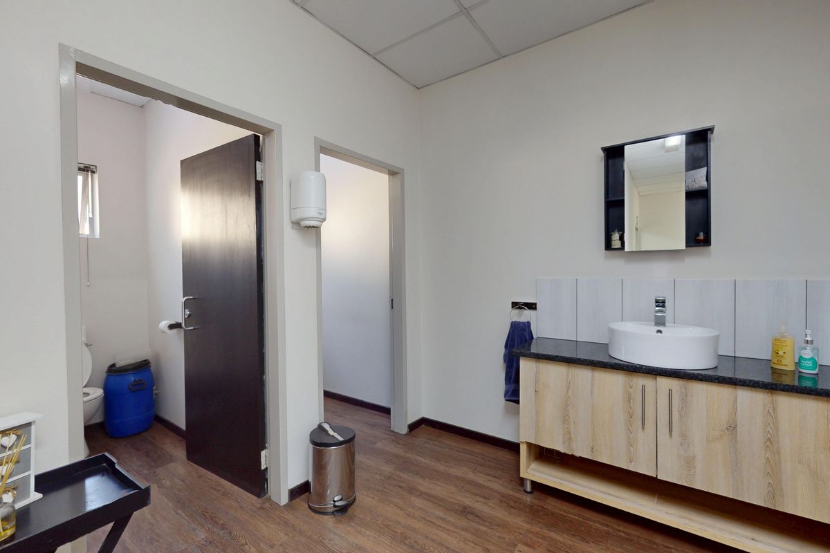 A functional bathroom area featuring a modern vanity cabinet with a countertop basin, tiled splashback, and a wall-mounted mirror.