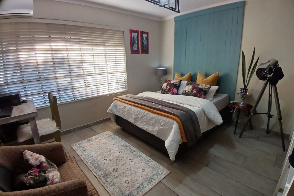 A well-maintained bedroom featuring tiled flooring, a decorative wooden headboard panel, and a wall-mounted air conditioning unit.