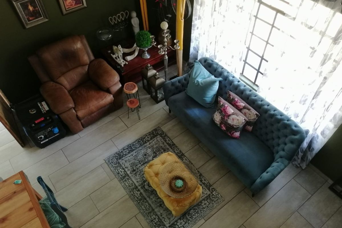 A high-angle view of a living room featuring tiled flooring and large windows, providing a bright and comfortable space.