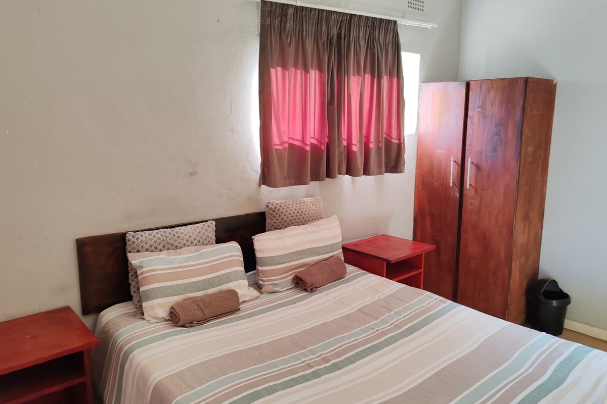 A simple bedroom featuring a window with curtain rail and basic wall finishes.