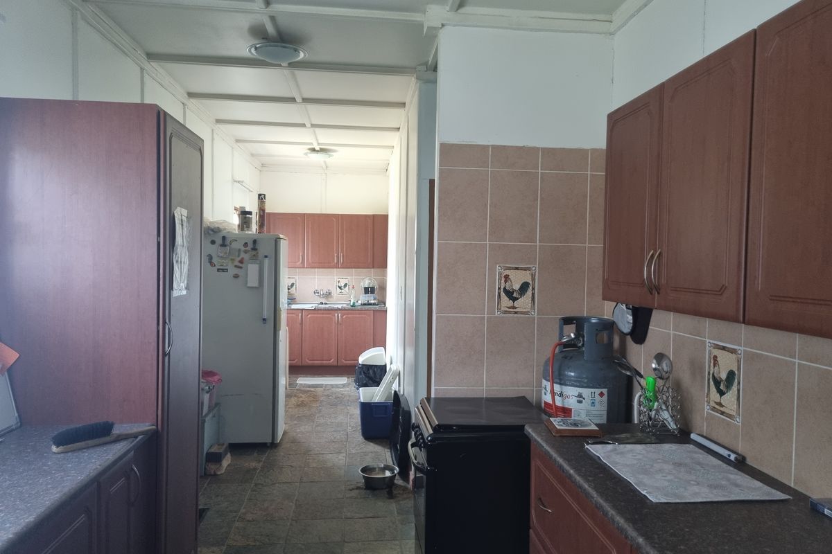 A functional kitchen featuring wood-tone cabinetry, tiled backsplash, and tiled flooring, offering a practical layout with ample storage space.