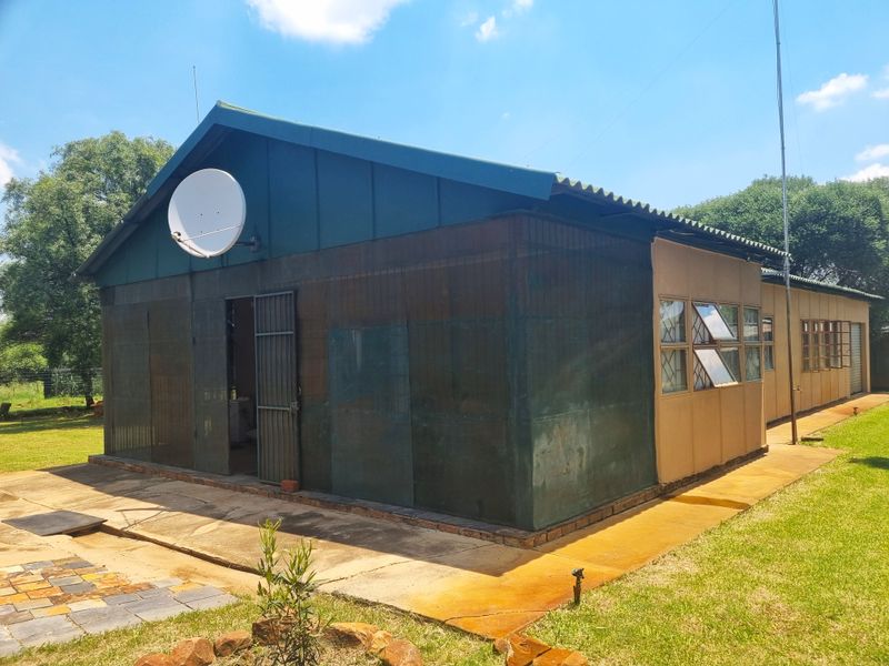 Rear view of a farm building featuring corrugated metal roofing, steel-framed windows, and a concrete apron surrounding the structure.