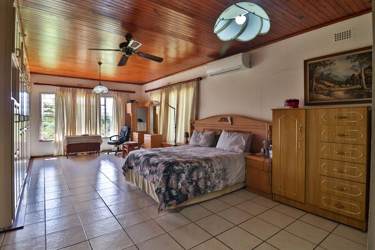 Spacious bedroom featuring a timber-clad ceiling, tiled flooring, built-in cabinetry, and a wall-mounted air conditioning unit.