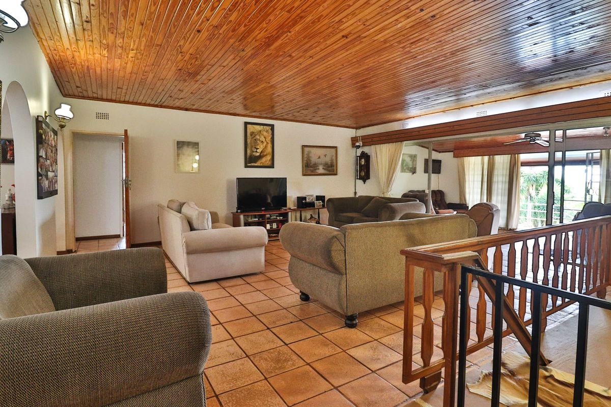 Spacious living room featuring a warm wooden tongue and groove ceiling, terracotta tiled flooring, and direct access to an outdoor patio area.