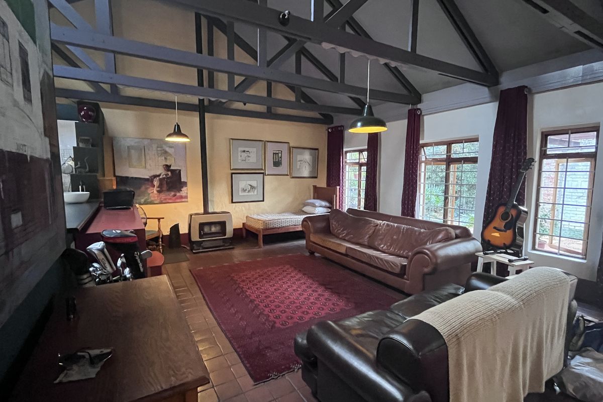 Spacious living area featuring high vaulted ceilings with exposed timber trusses, a cozy freestanding fireplace, and large windows providing natural light.