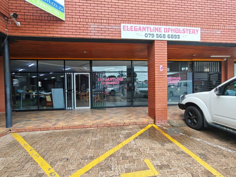 Front exterior view of a retail storefront featuring a brick facade, large glass display windows, and dedicated paved parking space.