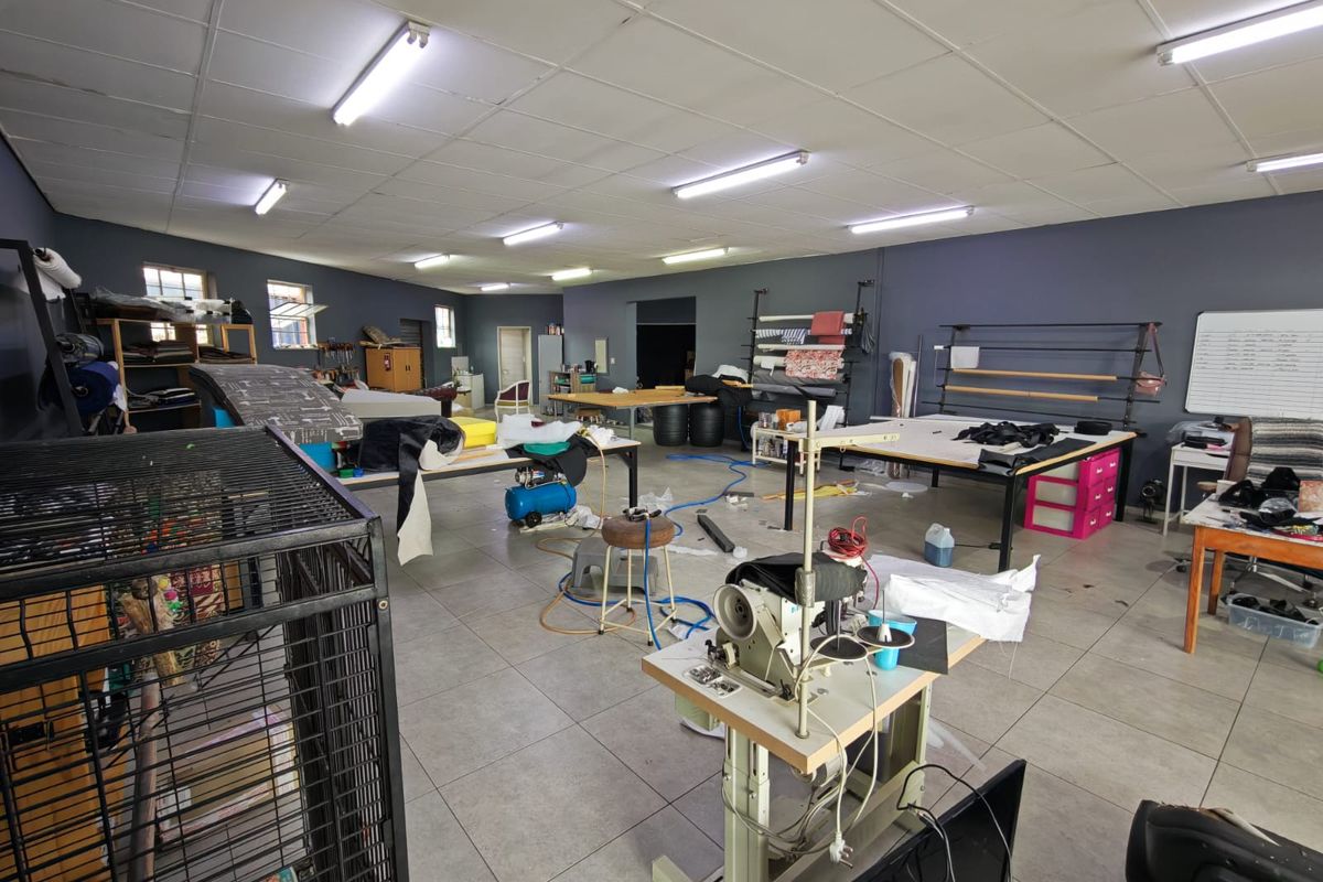 A spacious utility or workshop area featuring tiled flooring, suspended ceiling panels, and industrial fluorescent lighting, suitable for various commercial or production purposes.