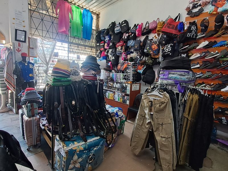 A retail shop interior featuring slatwall display systems for merchandise and a security gate at the entrance.