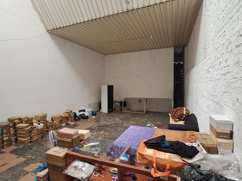 An industrial-style utility or storage space featuring exposed brick walls and a corrugated metal ceiling, offering a blank canvas for renovation.