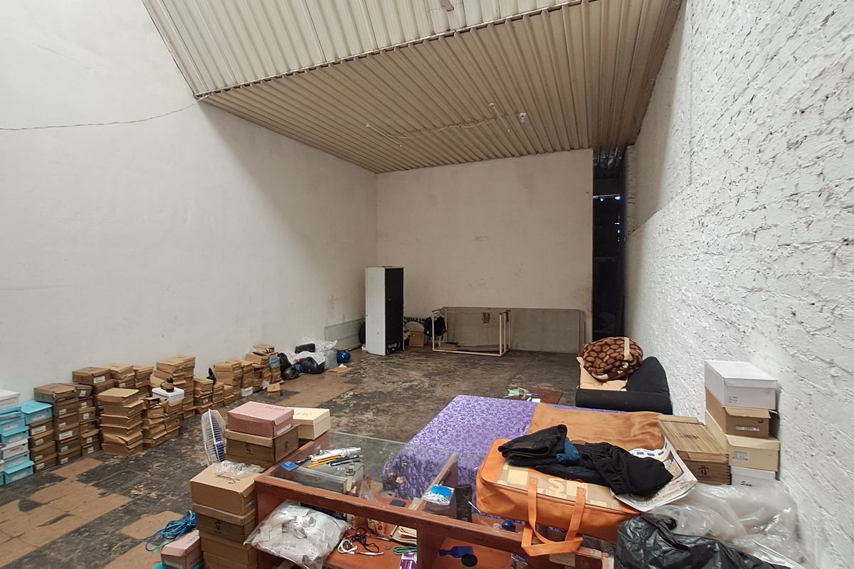 An industrial-style utility or storage space featuring exposed brick walls and a corrugated metal ceiling, offering a blank canvas for renovation.
