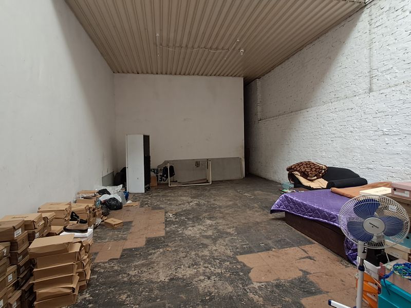 An industrial-style utility space featuring exposed brick walls, a corrugated metal ceiling, and worn concrete flooring, suitable for storage or workshop use.