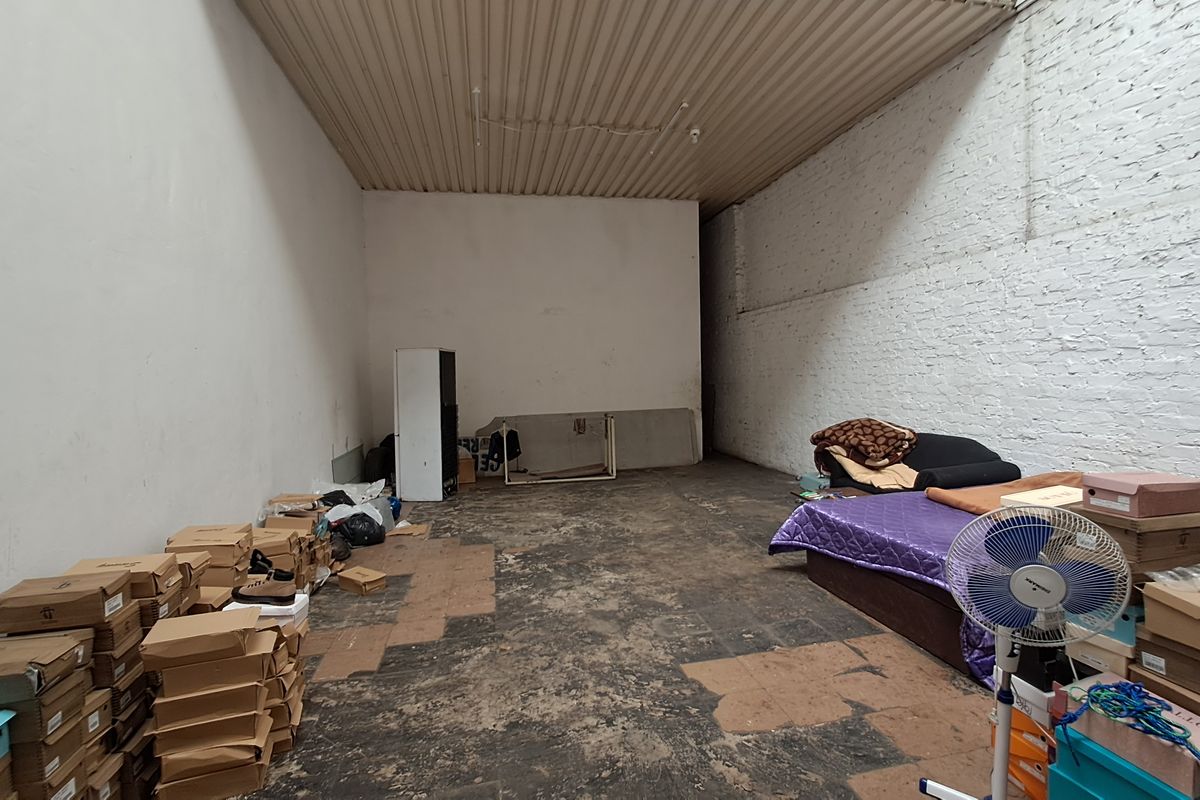 An industrial-style utility space featuring exposed brick walls, a corrugated metal ceiling, and worn concrete flooring, suitable for storage or workshop use.