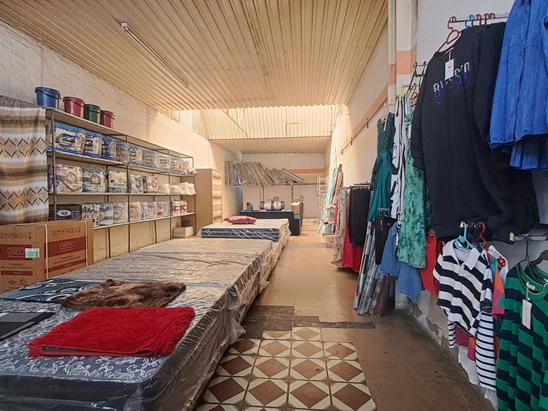 A commercial retail space featuring metal shelving, corrugated ceiling, and tiled flooring, currently utilized for merchandise display.