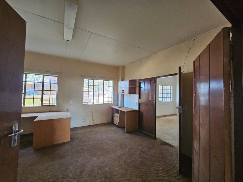 An empty office space featuring built-in desks, cabinetry, and timber doors, requiring cosmetic updates to the walls and flooring.