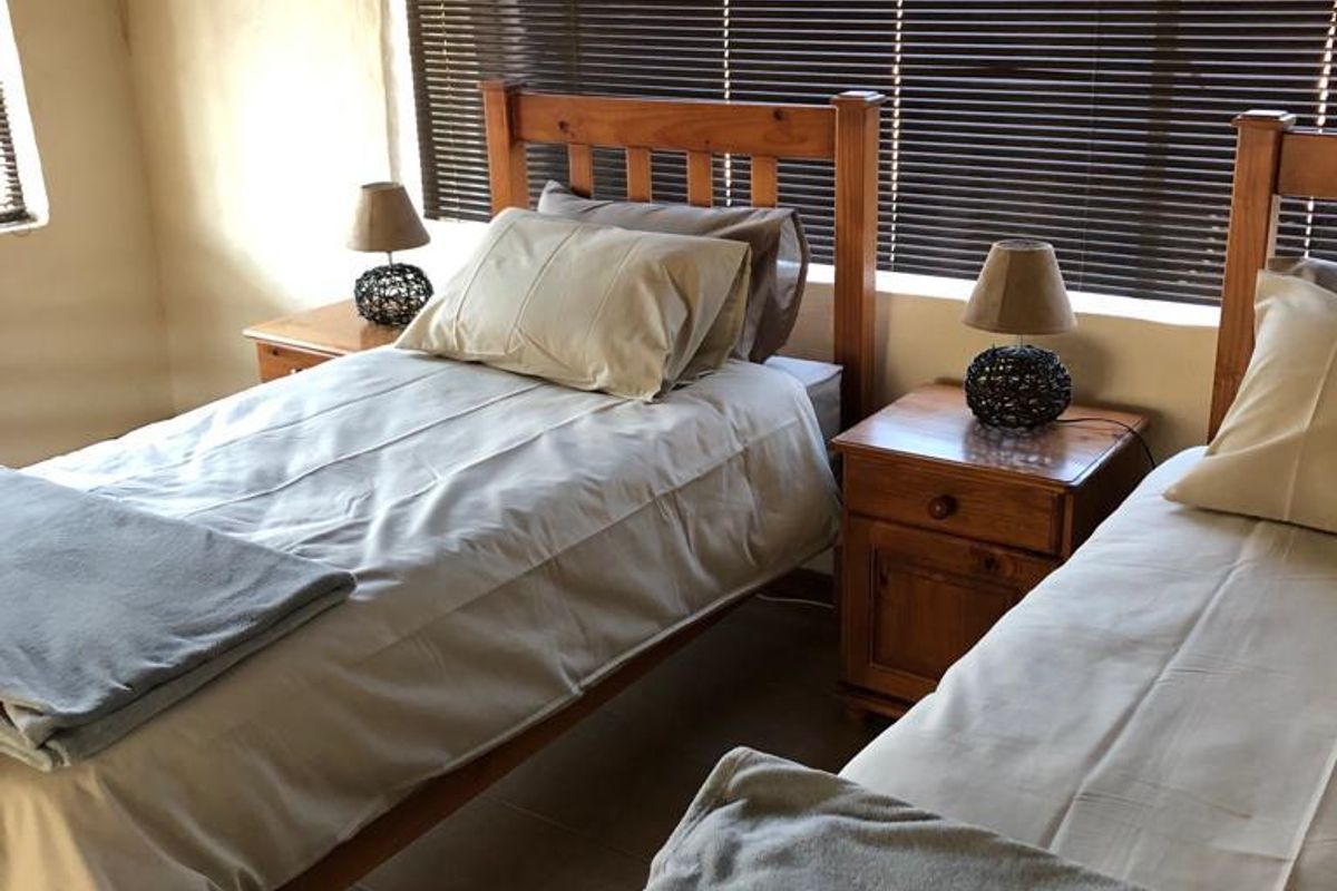 A bedroom featuring tiled flooring and venetian blinds, providing a functional space with natural light control.