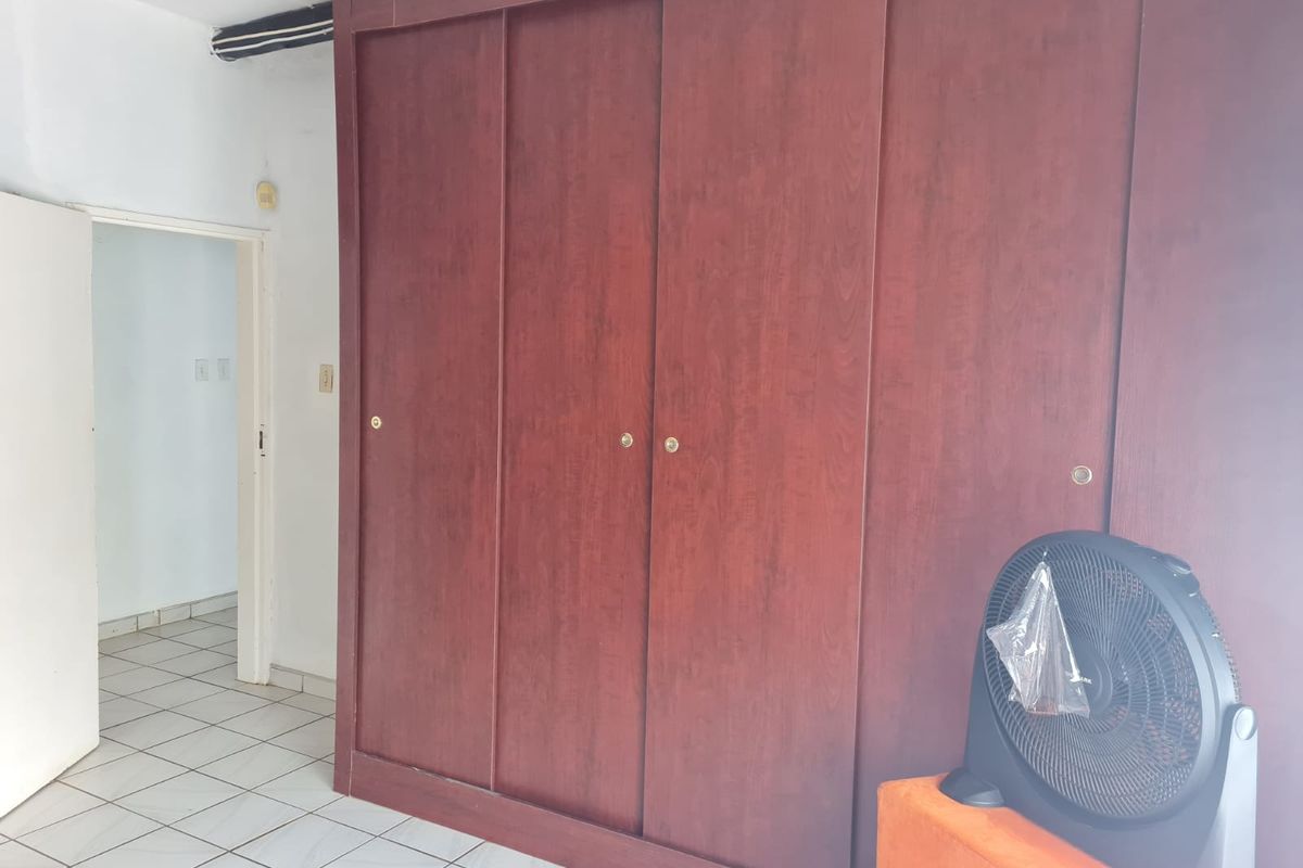 A bedroom featuring large built-in wooden sliding door wardrobes and neutral tiled flooring.