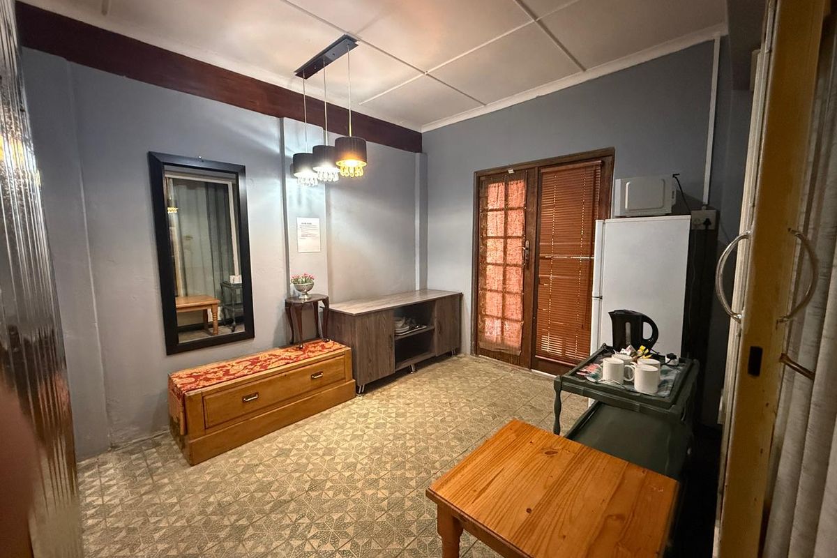 A functional living area featuring tiled flooring, pendant lighting, and a timber-framed glass door with venetian blinds.