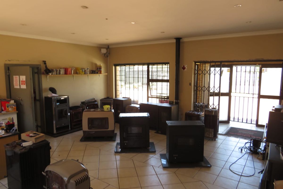 A commercial showroom space featuring tiled flooring, recessed lighting, and security-fitted windows and doors, currently utilized for displaying heating appliances.