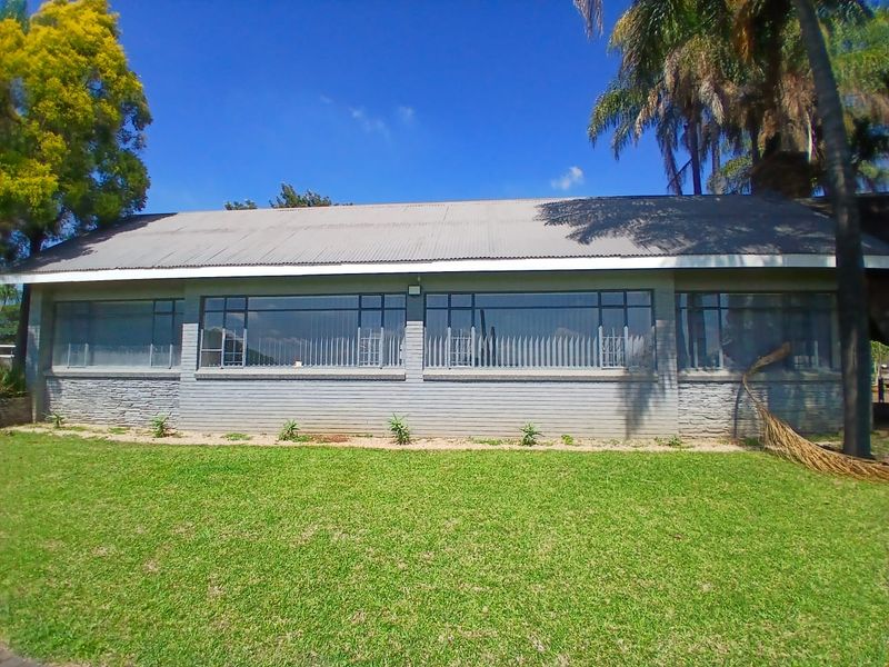 A view of the office building exterior featuring a corrugated metal roof, large windows, and a well-maintained lawn area.