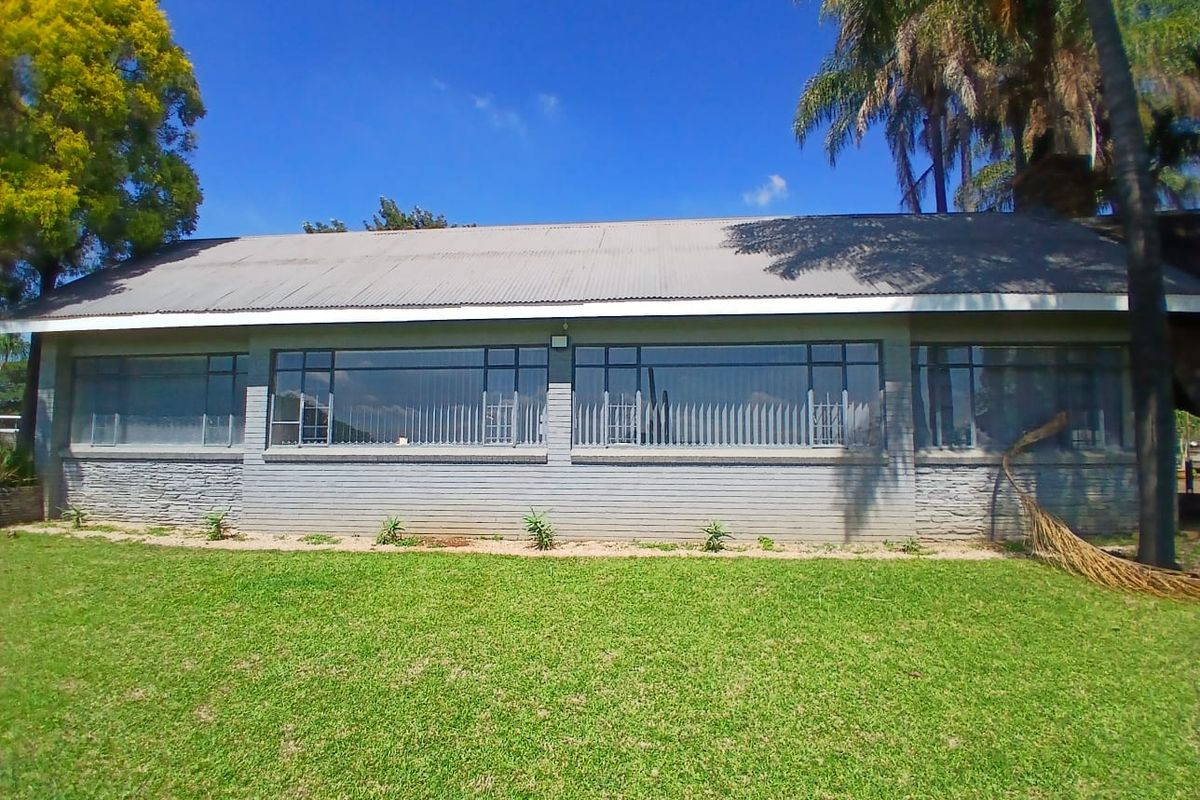 A view of the office building exterior featuring a corrugated metal roof, large windows, and a well-maintained lawn area.