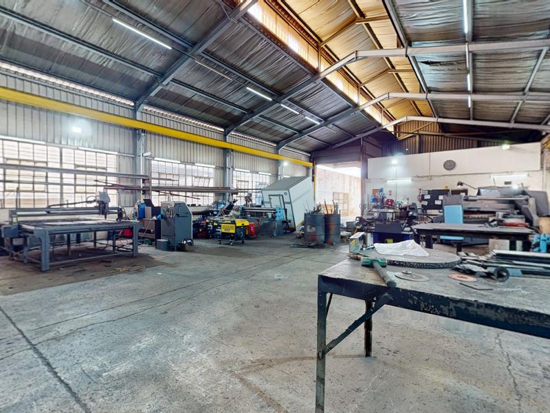 Spacious industrial workshop featuring a high-clearance steel portal frame, overhead crane rail, and durable concrete flooring, suitable for manufacturing or heavy-duty storage operations.
