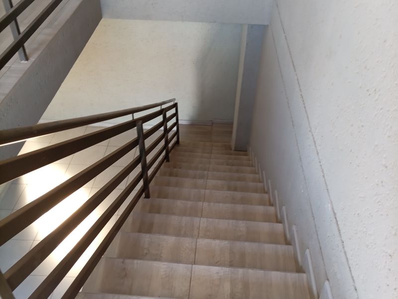 A functional interior staircase featuring tiled steps and a sturdy metal railing, providing access between levels in a commercial property.