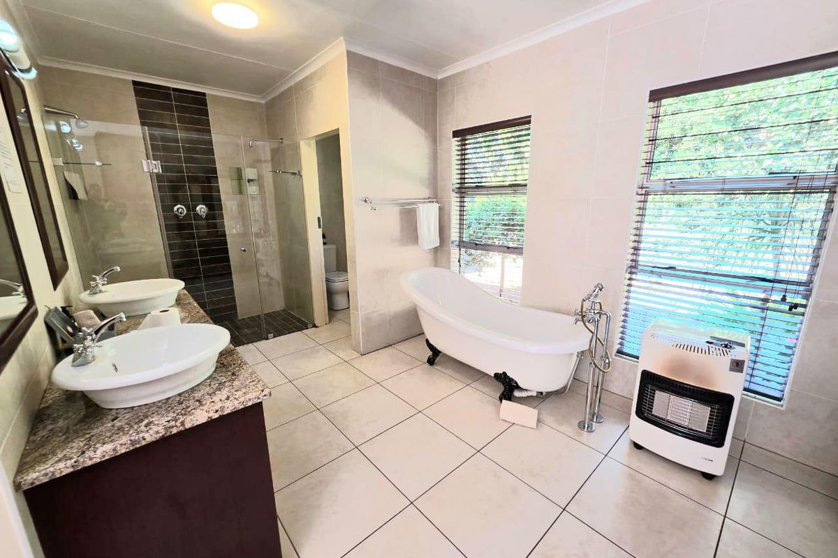 Spacious bathroom featuring a double vanity with granite countertop, a freestanding bathtub, and a separate walk-in shower with modern tiled finishes.