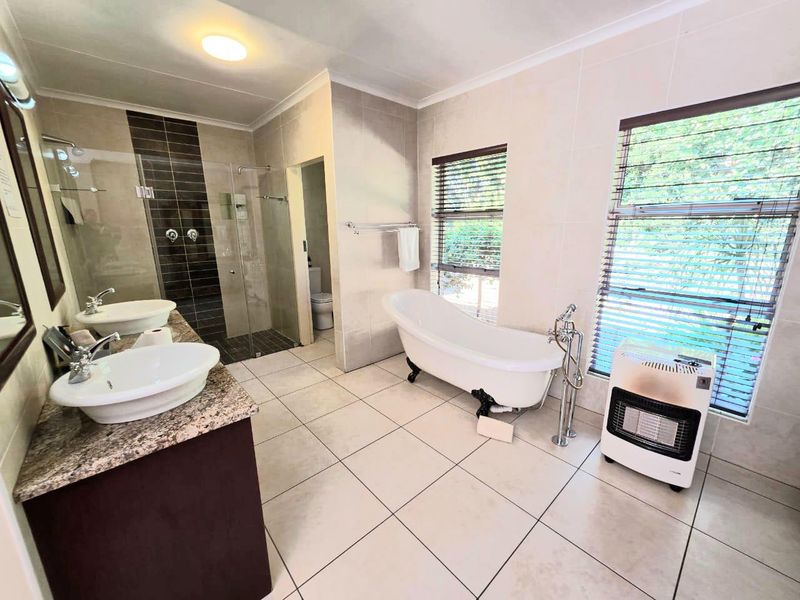 Spacious bathroom featuring a double vanity with granite countertop, a freestanding bathtub, and a separate walk-in shower with modern tiled finishes.