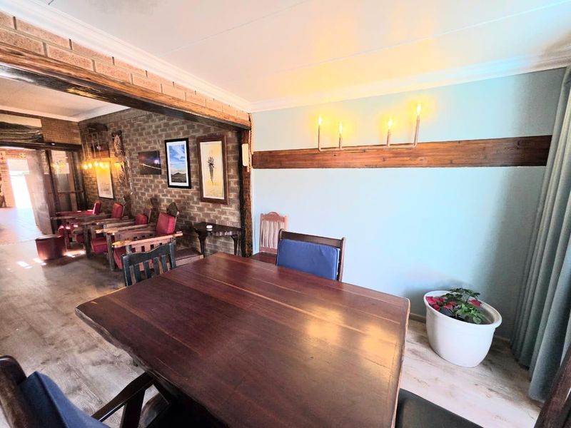 Open plan living and dining area featuring exposed brick walls, timber accents, and laminate flooring, creating a rustic and inviting atmosphere.