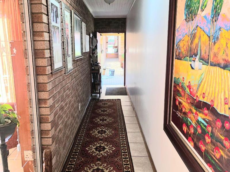 A bright hallway featuring exposed brickwork, tiled flooring, and a skylight, providing a clear transition between interior living spaces and the outdoor area.