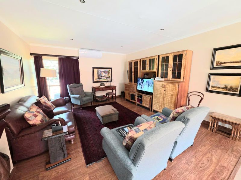 A comfortable living room featuring laminate flooring, recessed downlighting, and a wall-mounted split-system air conditioning unit.