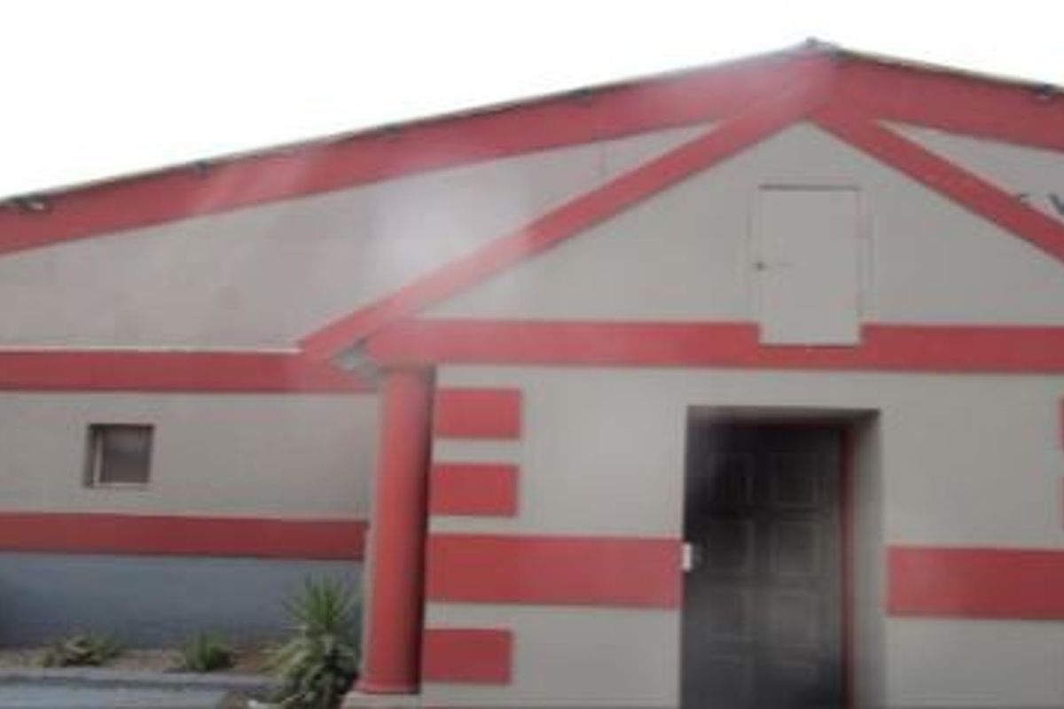 Front elevation of a commercial building featuring a gabled roof design, decorative columns, and a central entrance.