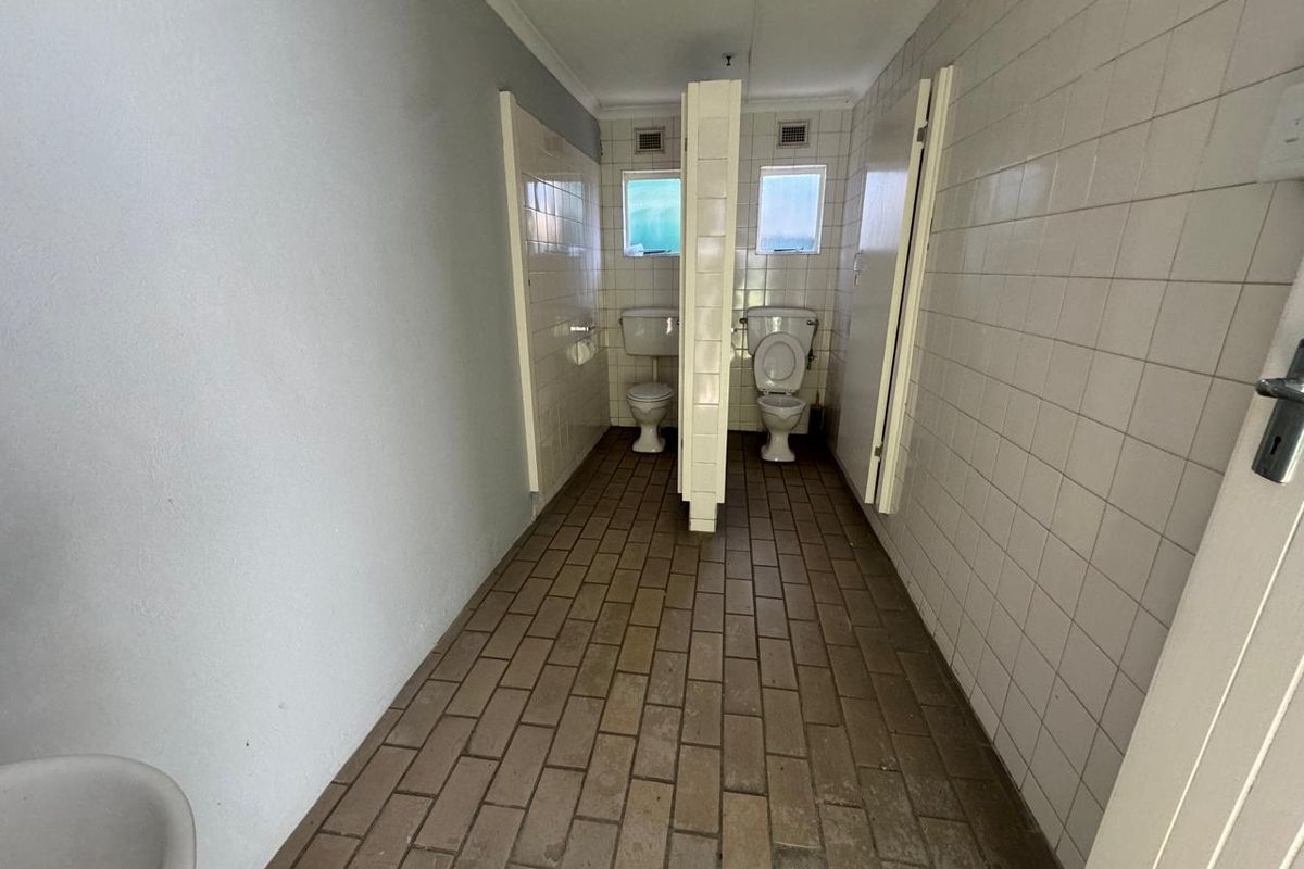 Industrial restroom facility featuring dual toilet stalls with tiled walls and flooring, providing functional utility space for a commercial or industrial property.