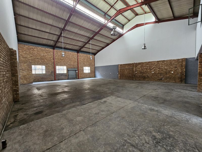 Spacious industrial warehouse unit featuring high exposed steel trusses, durable concrete flooring, and ample natural light through clerestory windows.