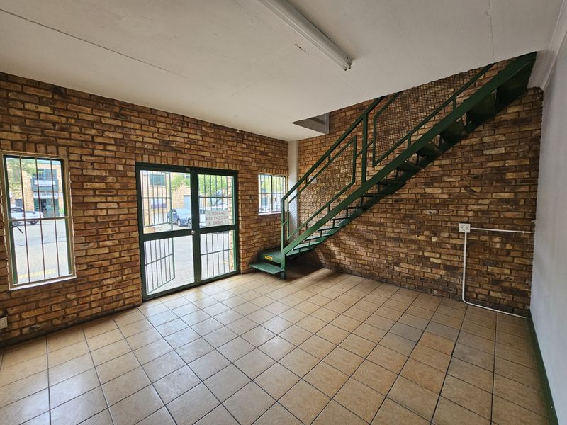 Industrial entry space featuring exposed brick walls, tiled flooring, and a metal staircase leading to the upper level.