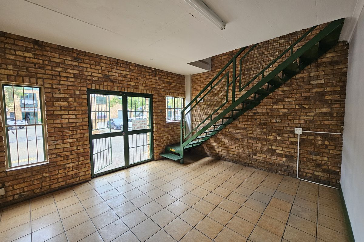 Industrial entry space featuring exposed brick walls, tiled flooring, and a metal staircase leading to the upper level.