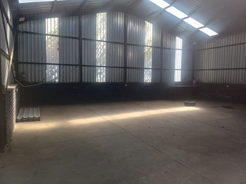Spacious industrial utility area featuring concrete flooring, corrugated metal walls, and natural light from integrated skylights.