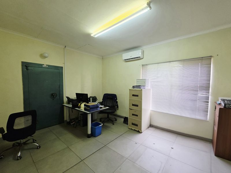 Functional office space featuring a secure steel vault door, split-system air conditioning, tiled flooring, and large window with venetian blinds.