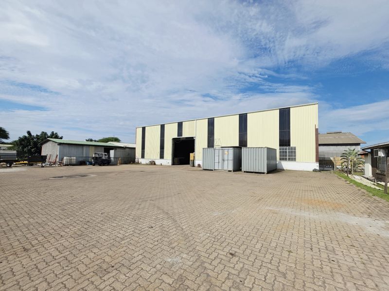 Industrial property featuring a large paved yard and a metal-clad warehouse structure with a high-clearance roller door entrance.