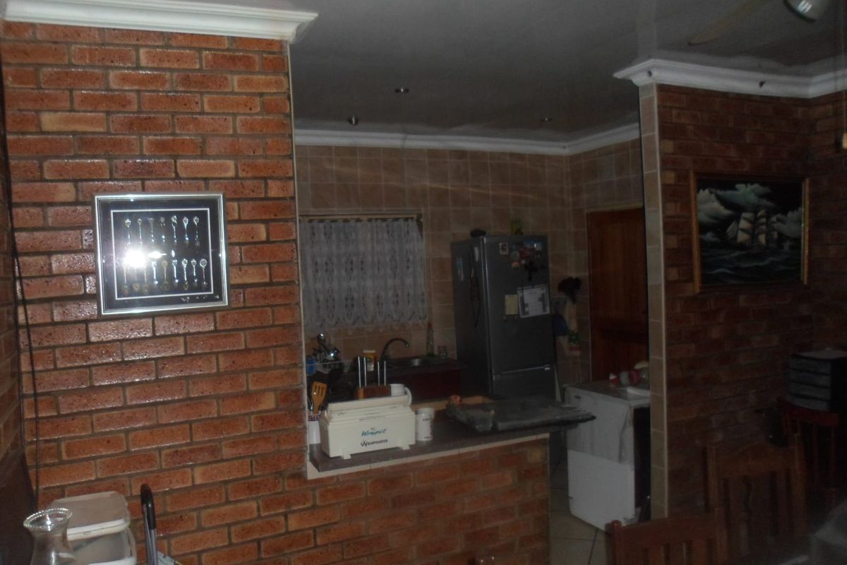 A functional kitchen area featuring exposed brick pillars, tiled splashbacks, and a breakfast counter, providing a rustic aesthetic within the home.