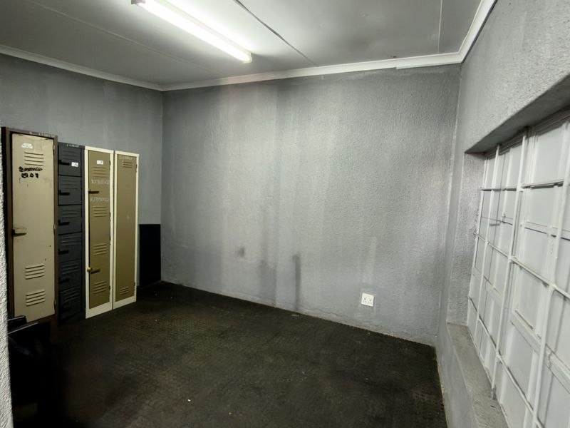 A functional utility or storage space featuring built-in metal lockers, security-barred windows, and durable flooring, suitable for various commercial storage needs.