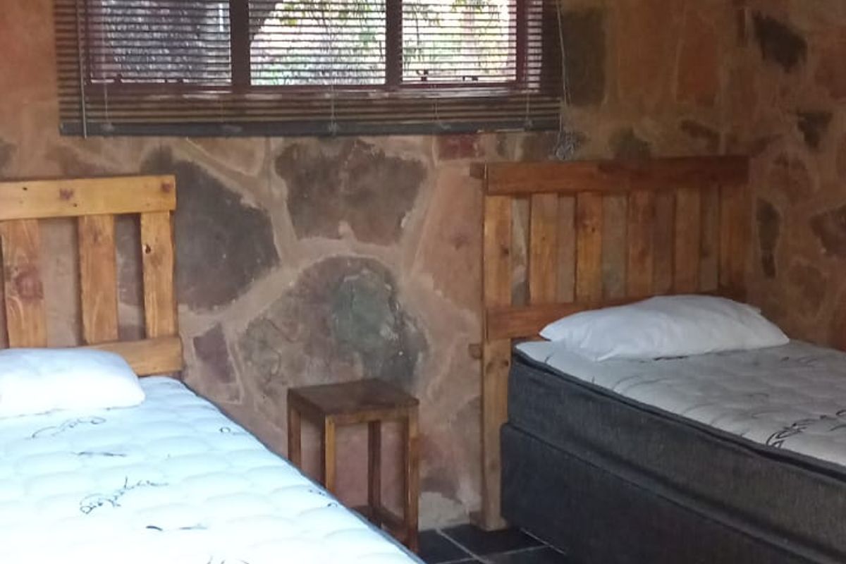 Rustic bedroom featuring exposed natural stone walls, slate tile flooring, and a corrugated metal ceiling, providing a unique farm-style aesthetic.