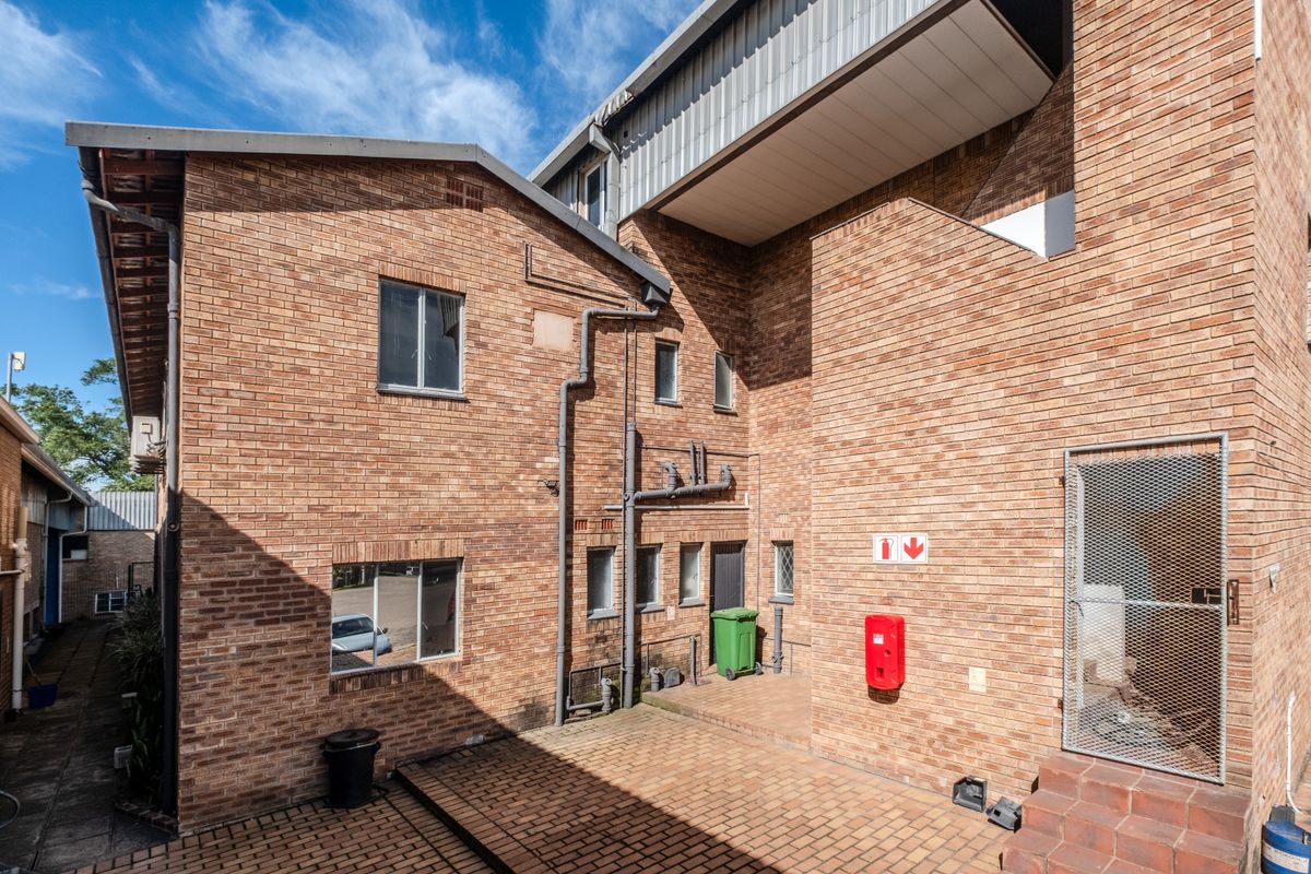 Rear exterior view of the office building featuring face-brick facade, paved courtyard area, and integrated fire safety equipment.