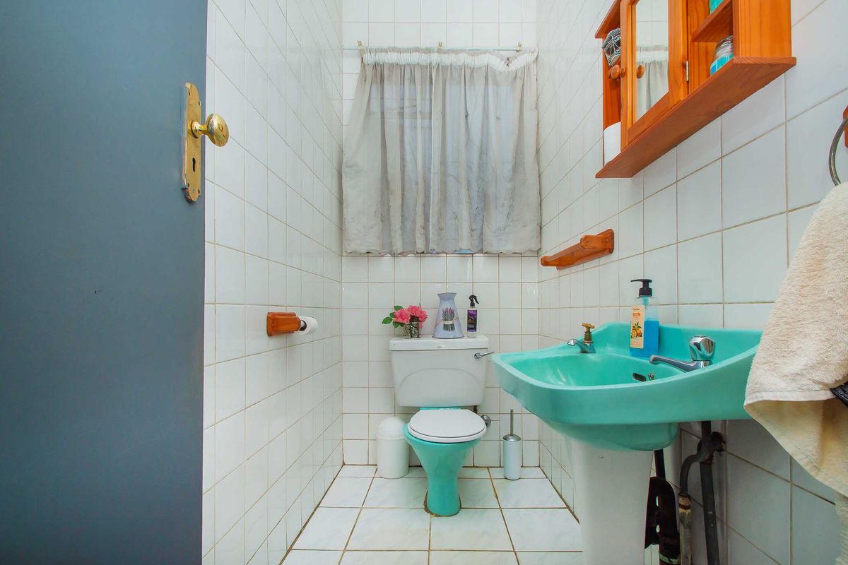 A compact bathroom featuring dated turquoise sanitary ware, full-height wall tiling, and ceramic floor tiles, offering potential for a modern renovation.